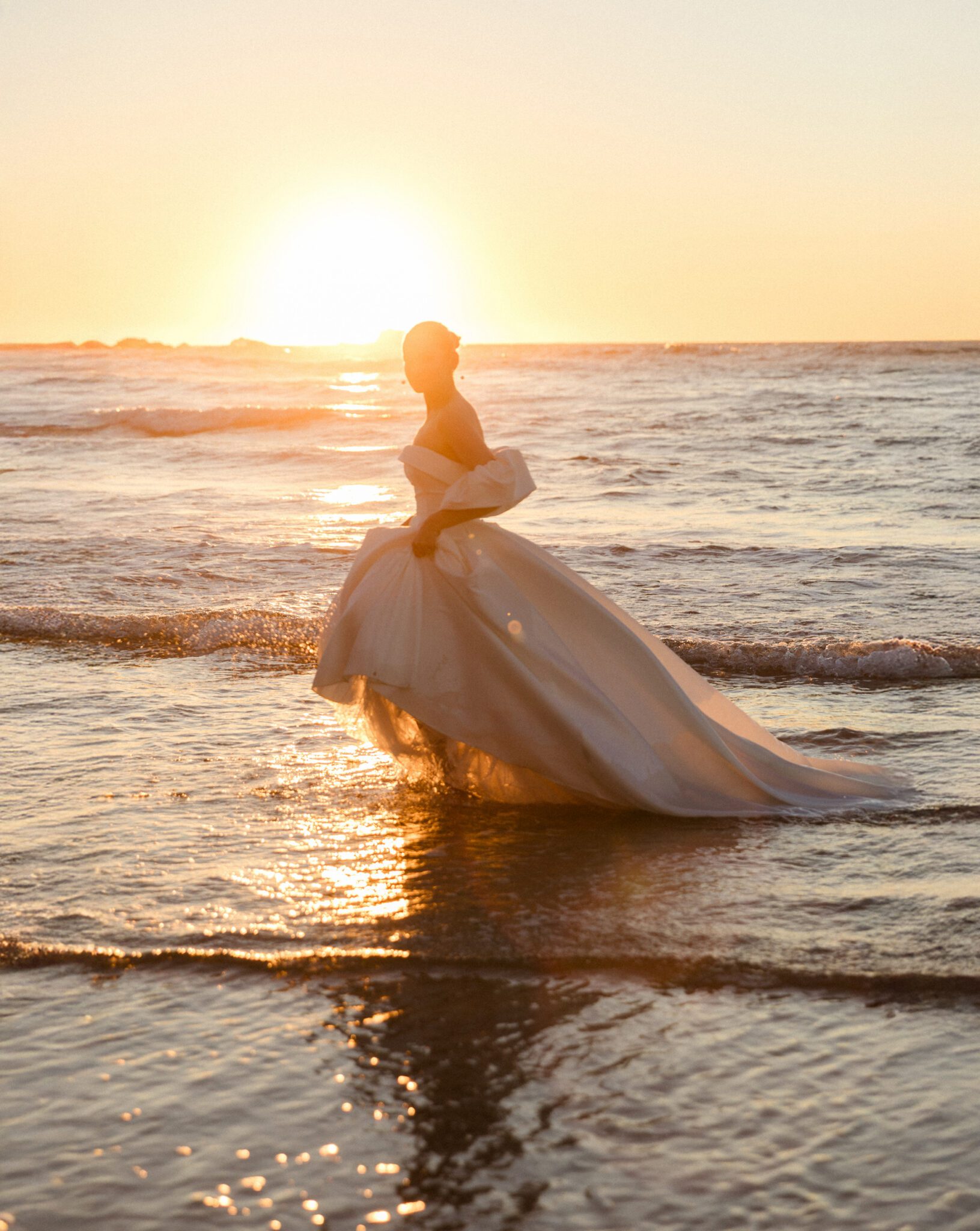 Elegant bride in a flowing wedding gown against the Algarve coastline
