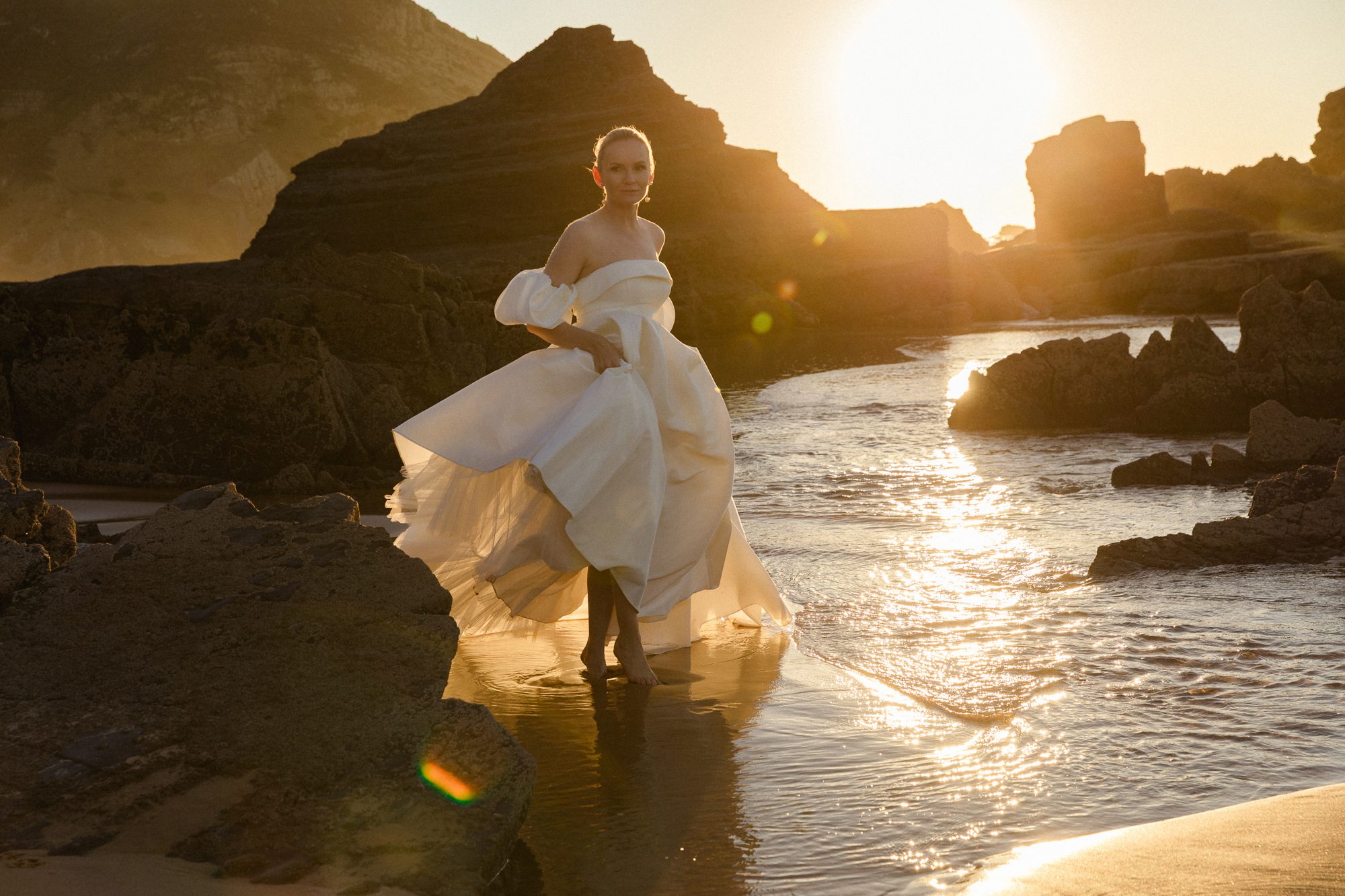 Elegant bride in a flowing wedding gown against the Algarve coastline
